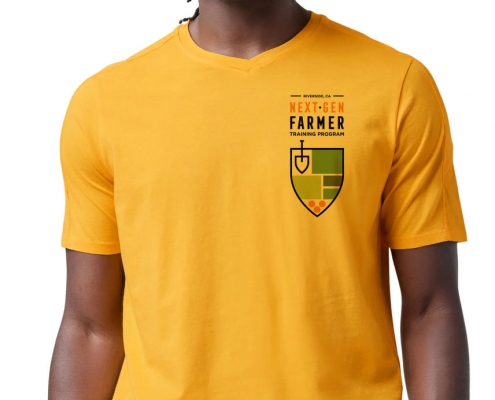 Black man wearing golden-yellow short sleeved t-shirt with Next-Gen Farmer logo in the breast pocket area